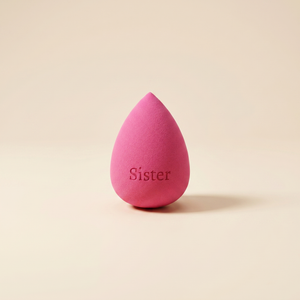 Růžový beauty blender kapkovitého tvaru s gravírovaným nápisem Sister
