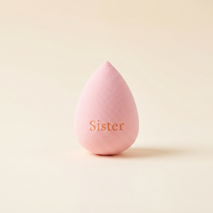 Světle růžový beauty blender kapkovitého tvaru s gravírovaným nápisem Sister